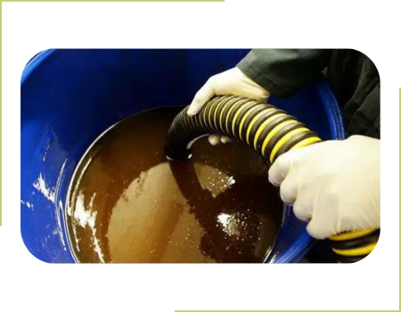 A person collecting used cooking oil with a vacuum hose.