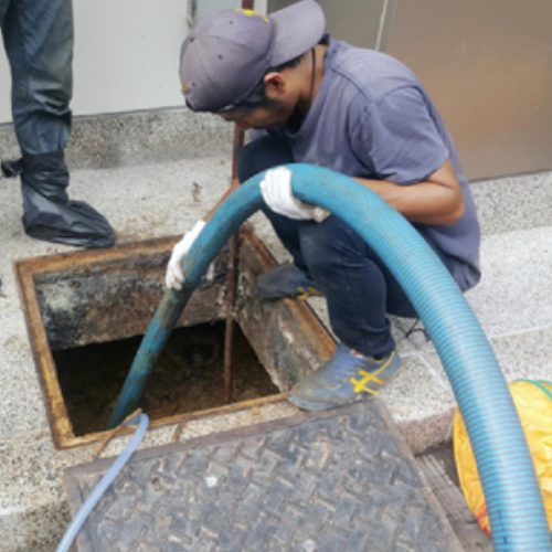 A man is working on the side of a drain.