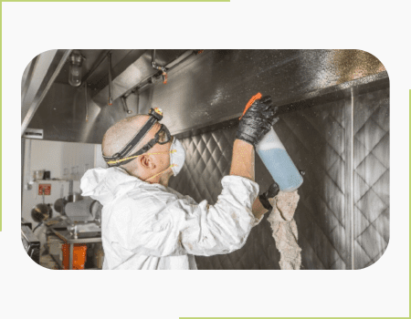 A man in white jacket and black gloves sprays water on the wall.