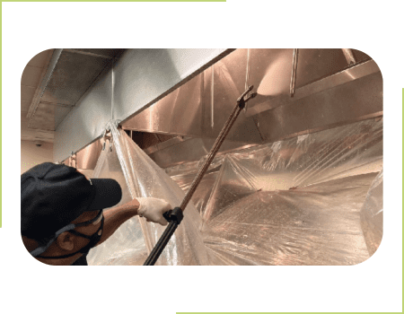 A man is cleaning the ceiling of an industrial building.