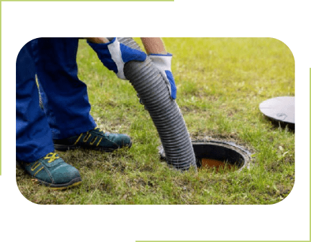 A person in blue pants and gloves is using a hose to clean the sewer.